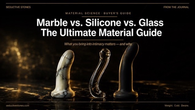 Three luxury adult toys side by side: white veined marble, clear glass, and dark silicone on black marble surface with gold lighting